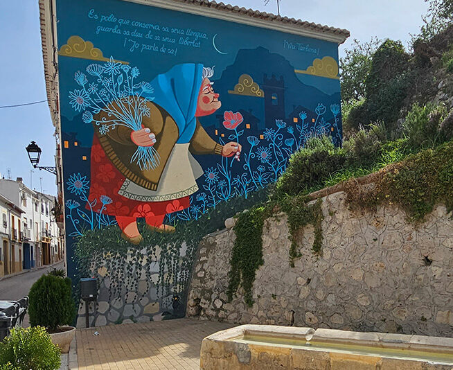 Mural colorido de una mujer con flores en una calle de Tarbena